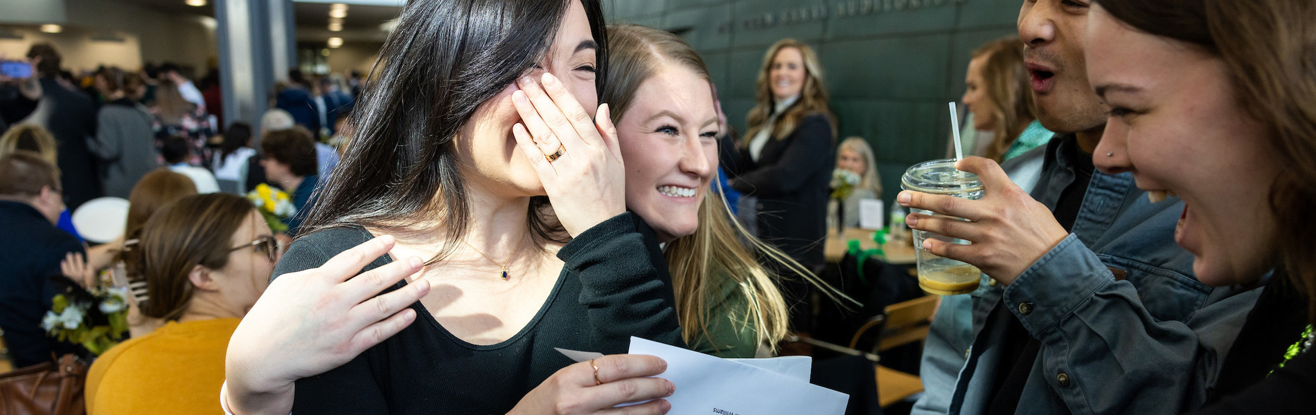 Student holding her Match Day letter surrounded by friends celebrating with her 