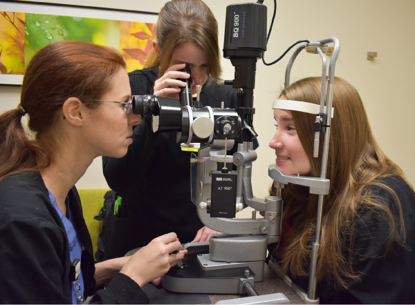 Allie Copple (center) peers into the teaching scope during a practice examination.