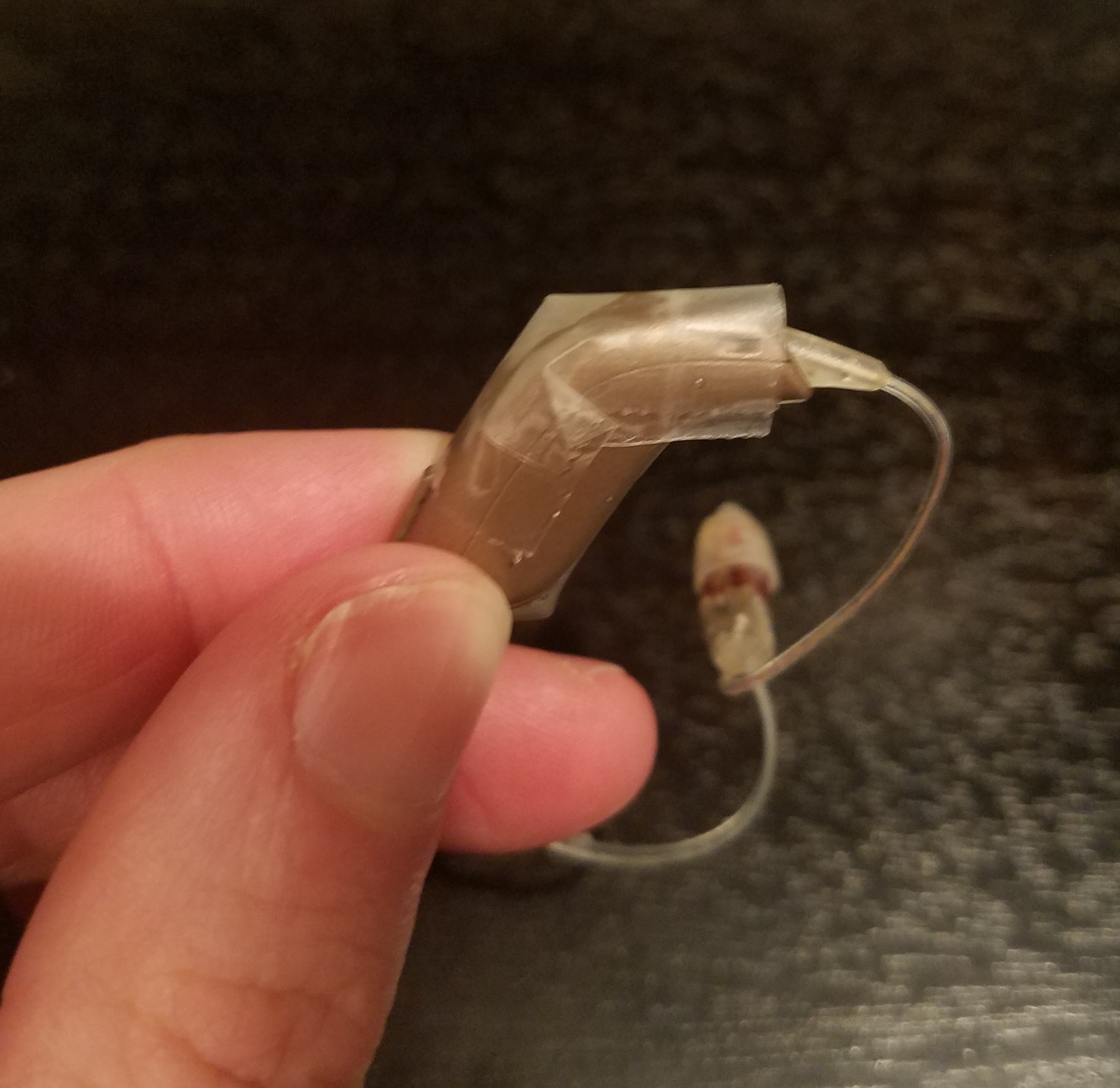 Hearing aid with tape over the microphone