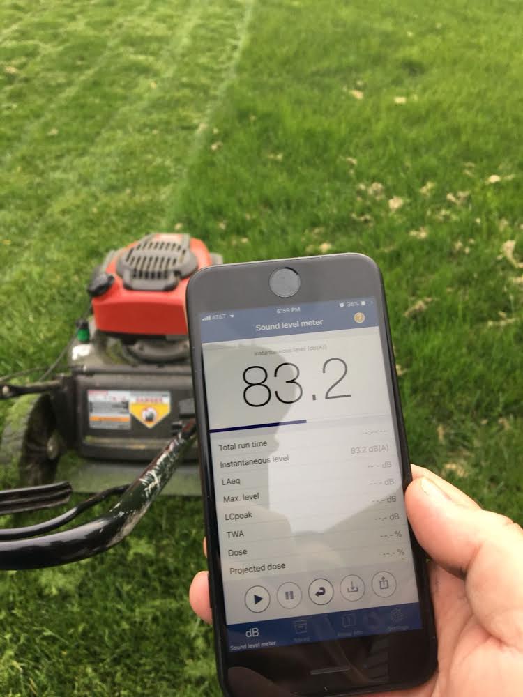 Decibel app on phone measuring a lawn mower