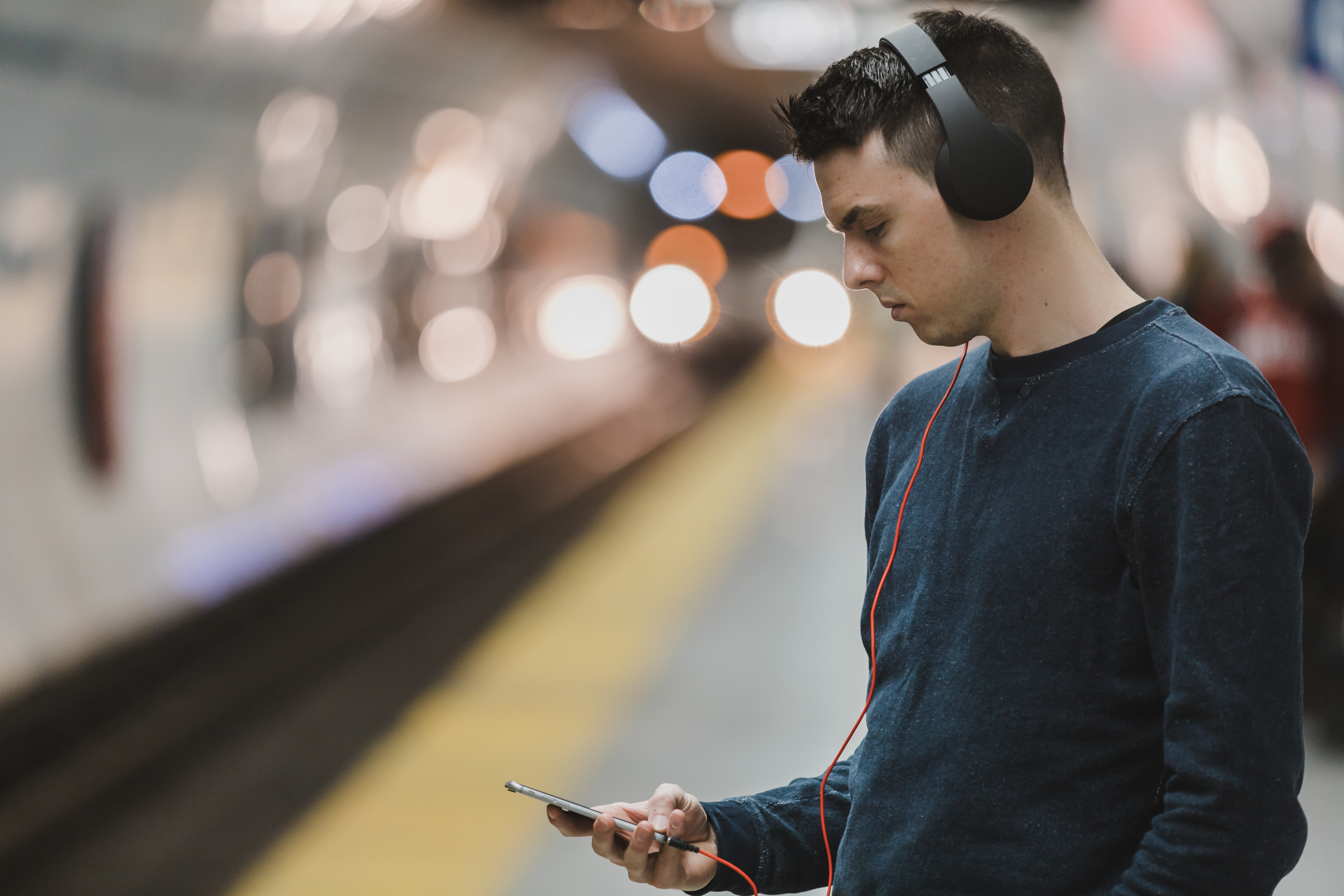 Man listening to headphones at subway stop