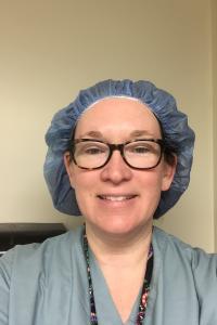 Selfie of Nora Royer wearing a surgical bouffant and scrubs