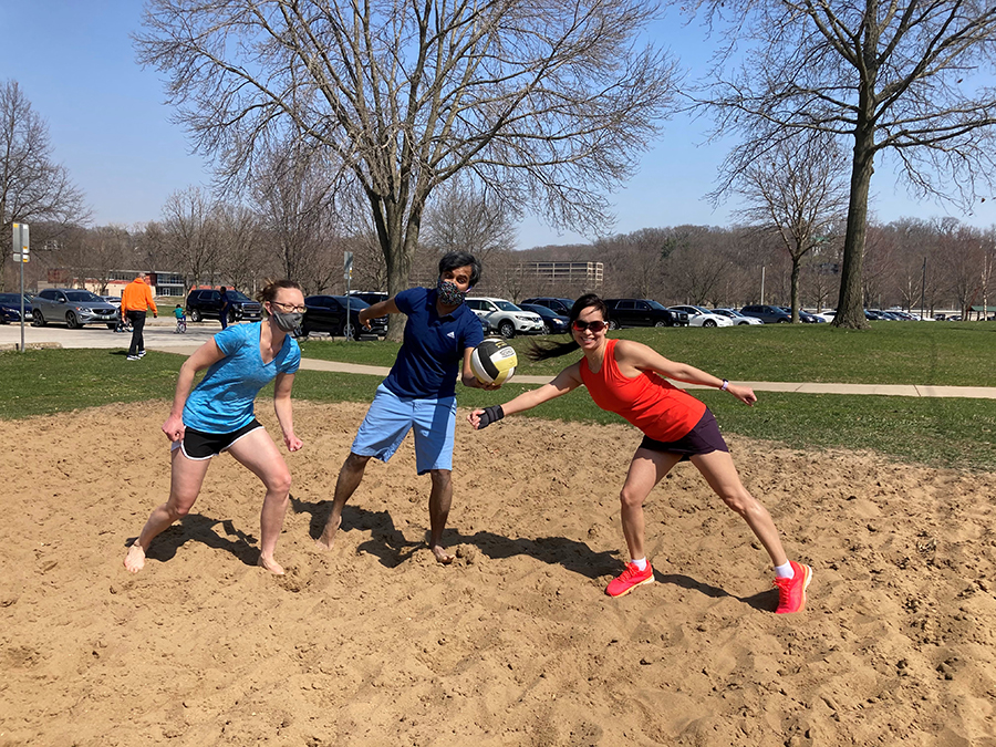 3 fellows playing sand volleyball