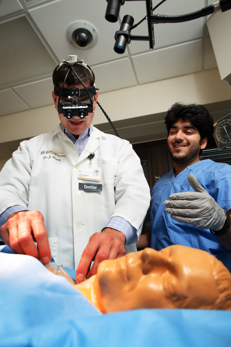 Dr. John Keech and a medical trainee perform a simulation procedure on a medical mannequin.