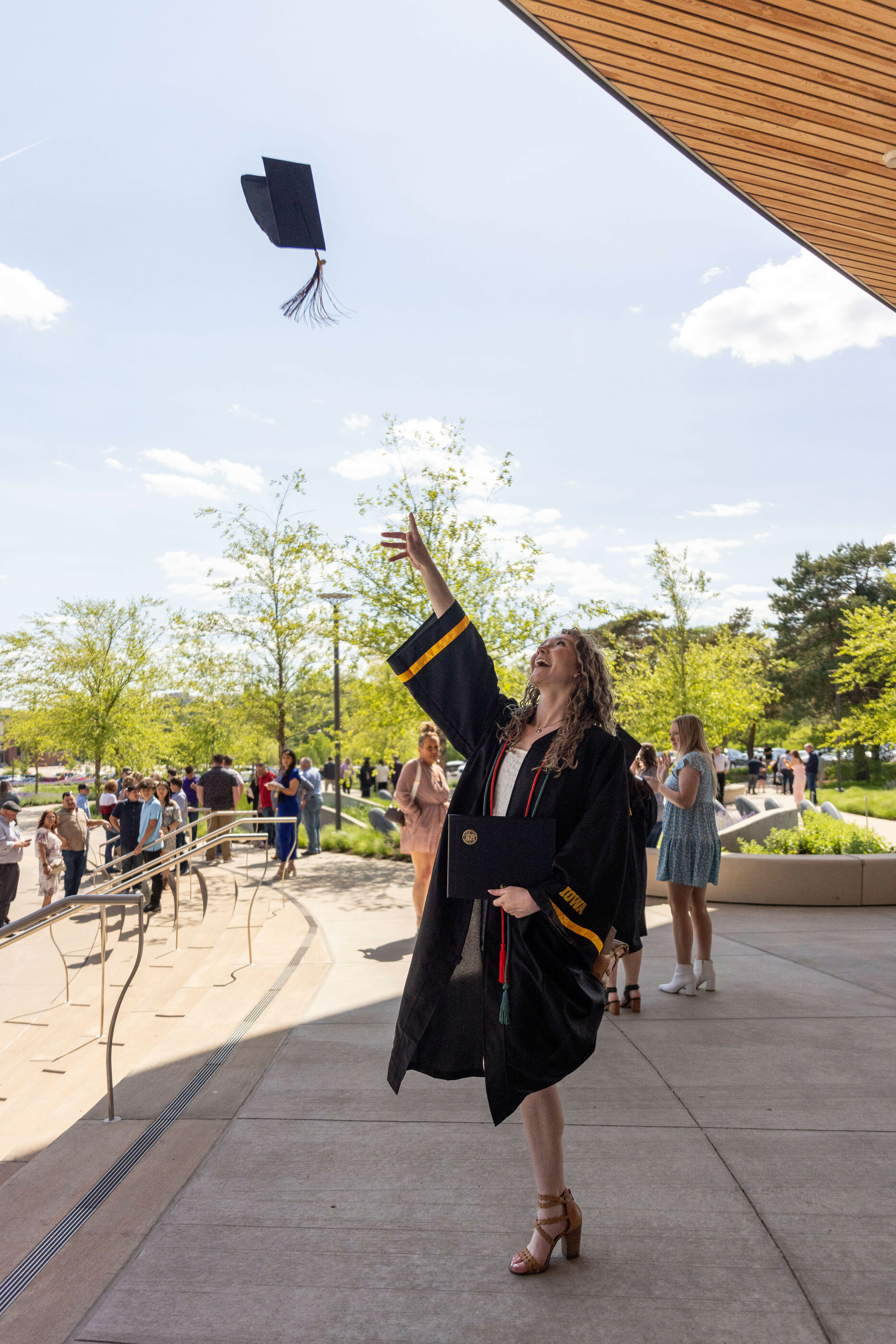 A student in graduation robes throws her cap