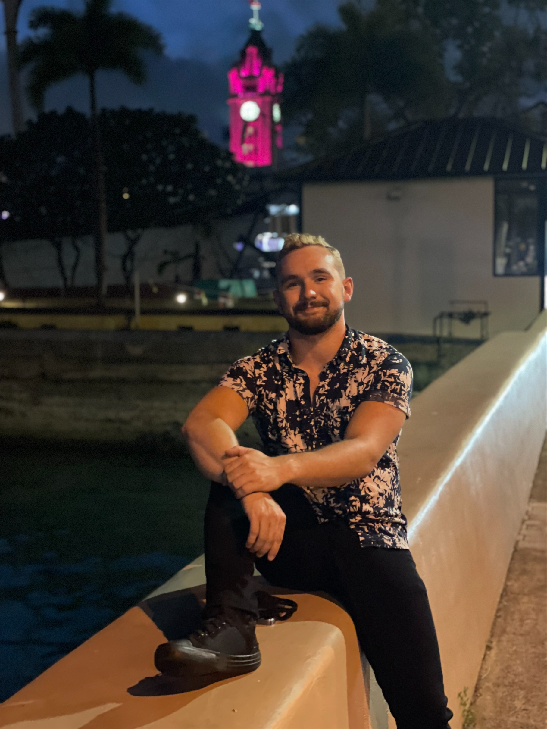 Joshua Lingo sits cross-legged in a floral shirt.