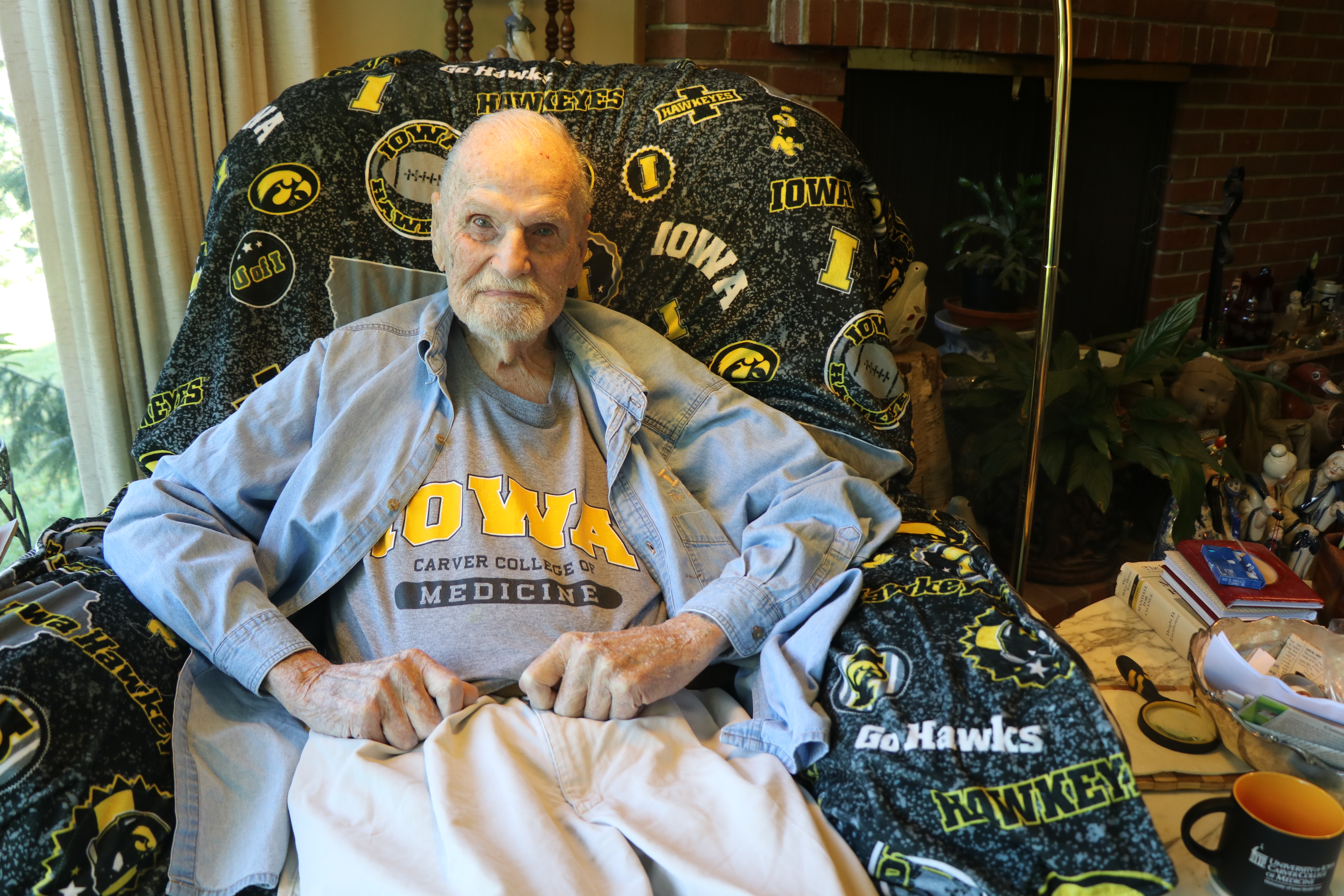 Portrait of Rufus Kruse, MD sitting in an armchair at home, wearing a Carver College of Medicine t-shirt