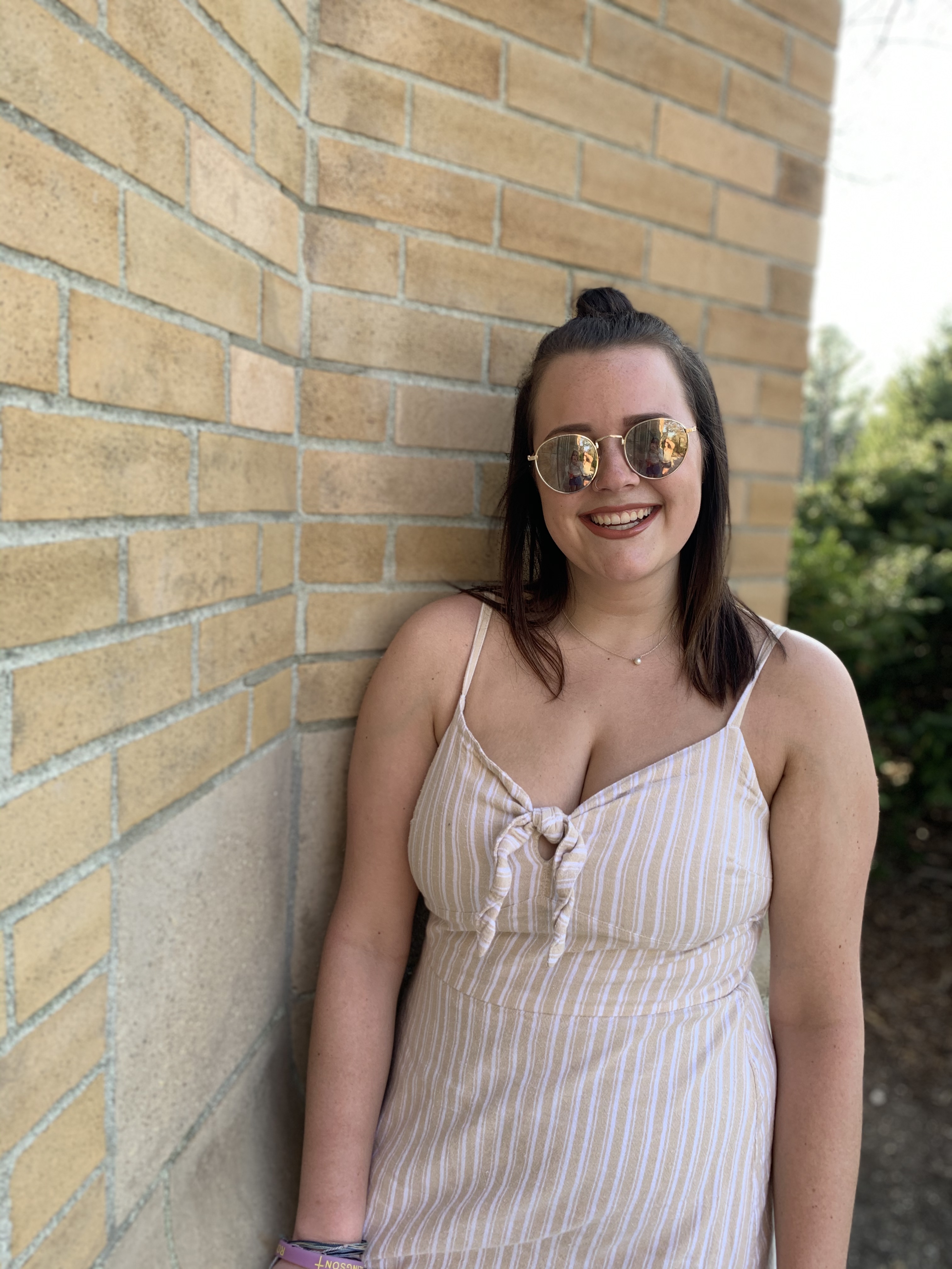 Lizzie Hannan wearing sunglasses outdoors next to a brick wall