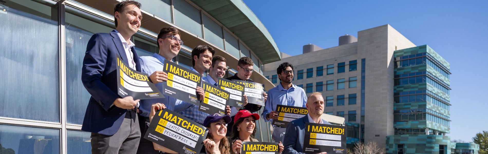 A group of medical students pose on campus with their "I Matched" signs