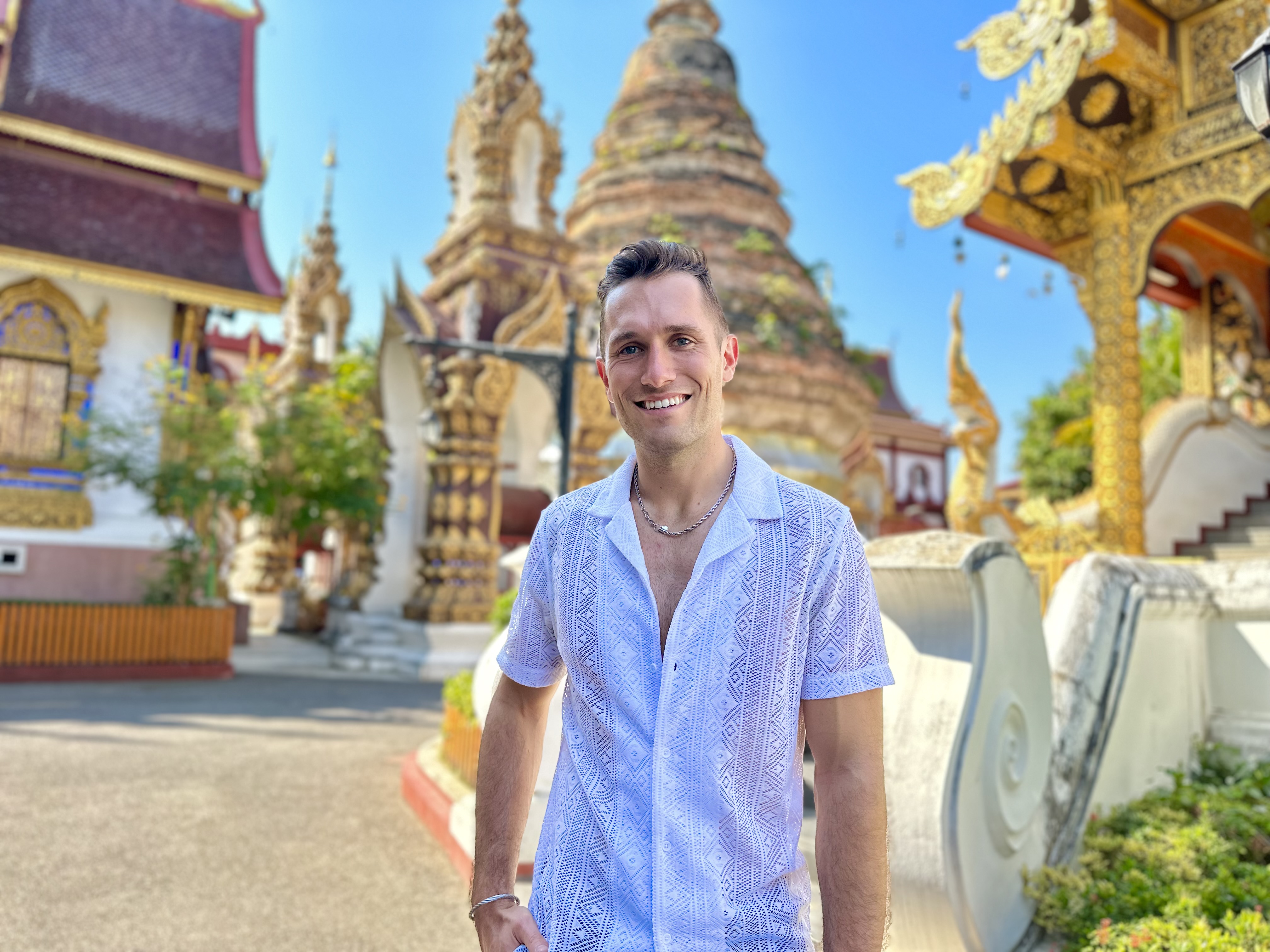 Nathen Spitz stands in front of a colorful temple in Thailand.