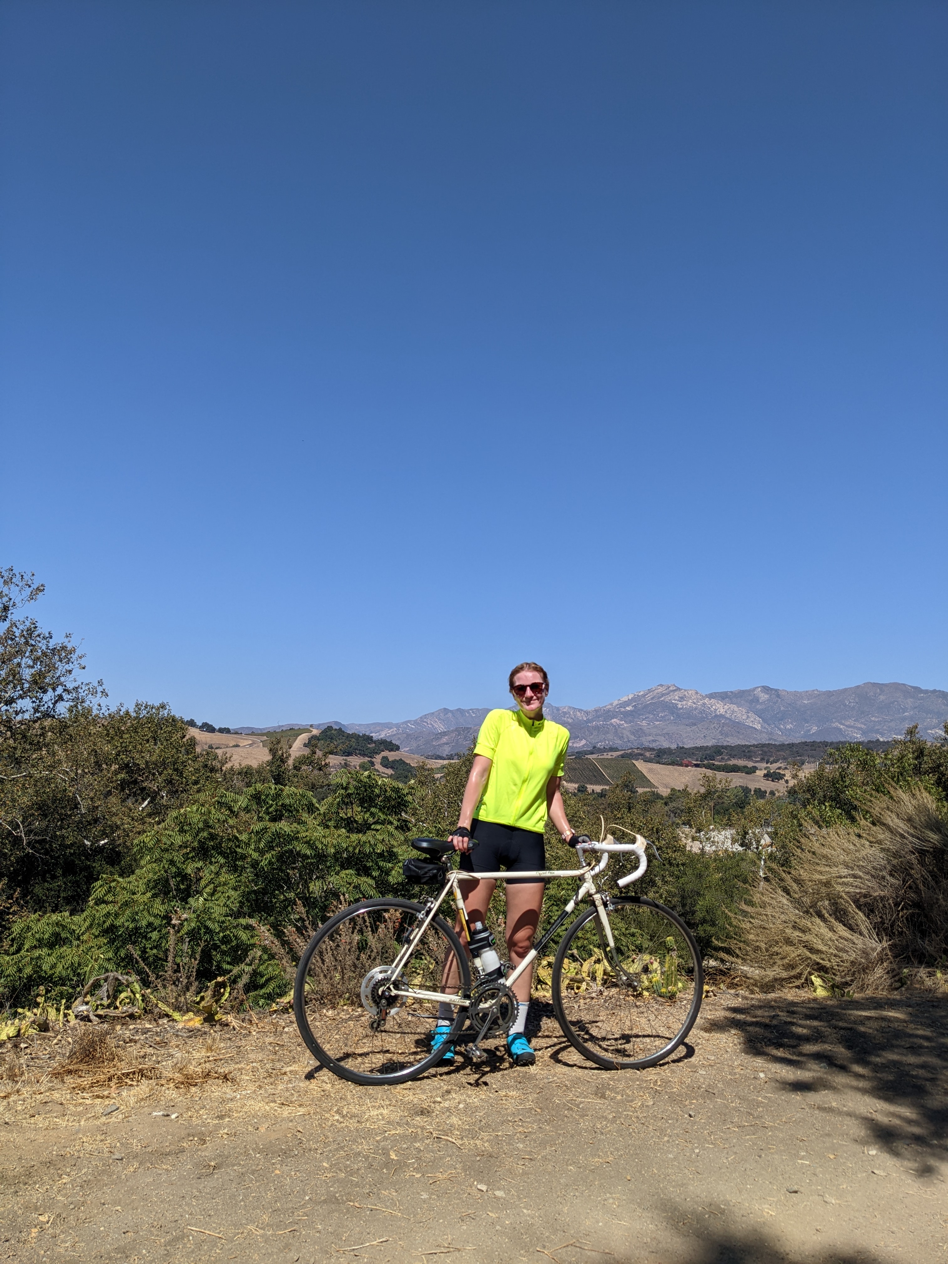 Claire Carmichael stands next to her bicycle in cycling clothes