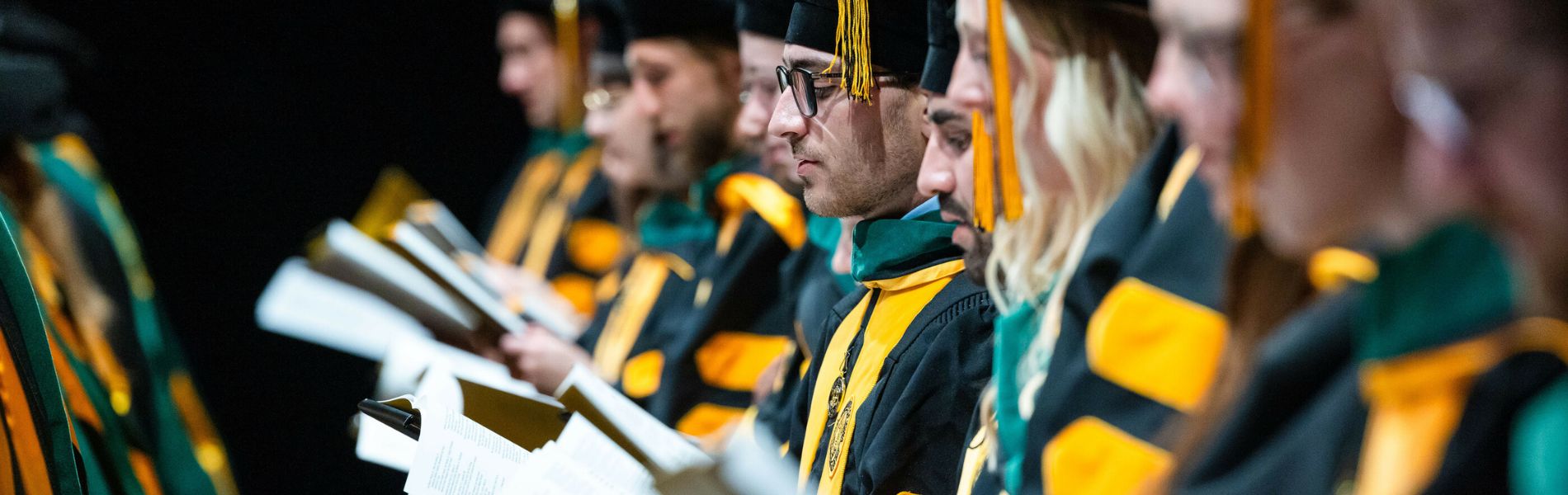 Students in graduation robes read the Hippocratic Oath