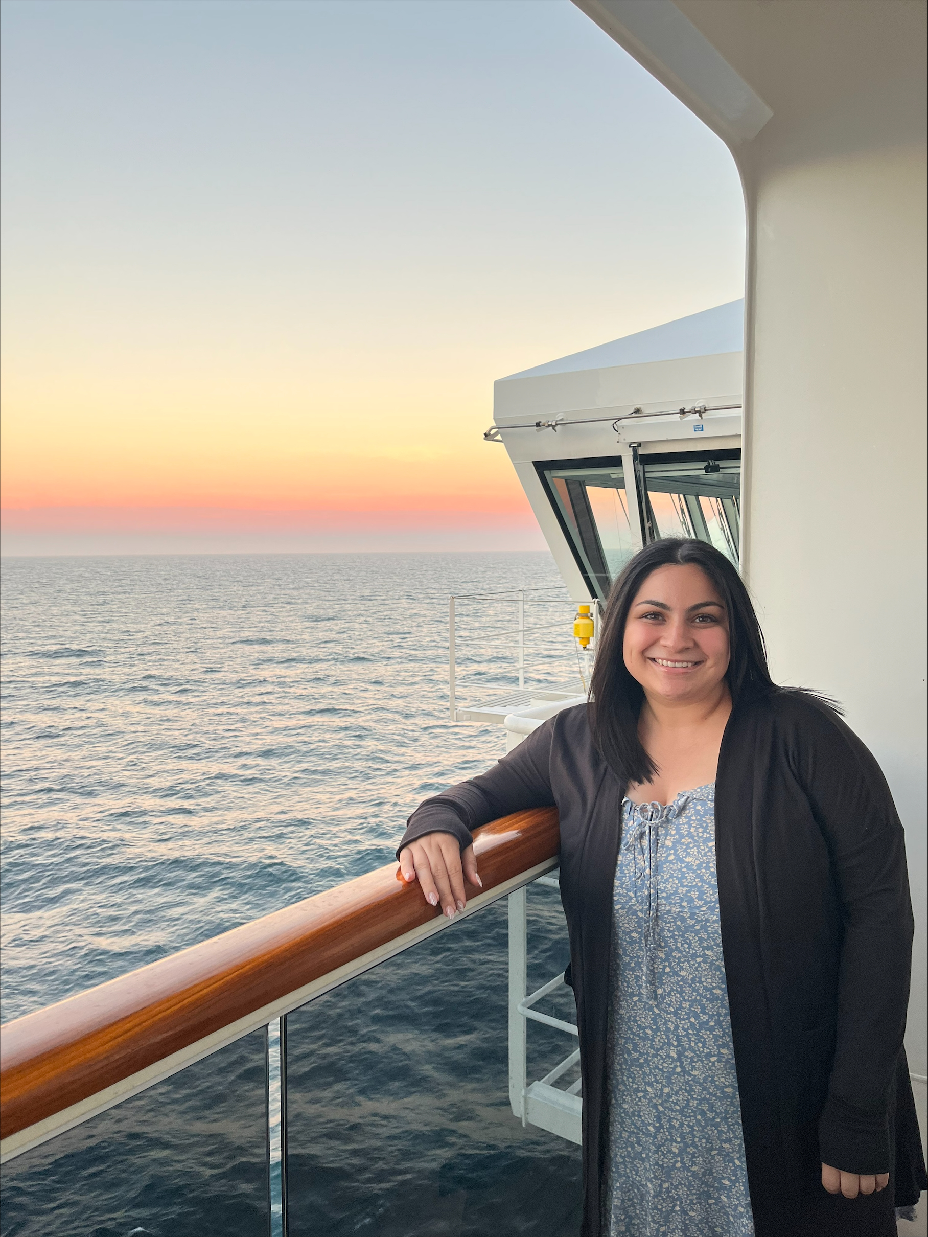 Misty Perez stands on the deck of a boat with a sunset in the background