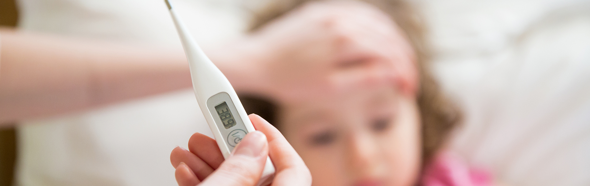 Care giver holds digital thermometer near patient