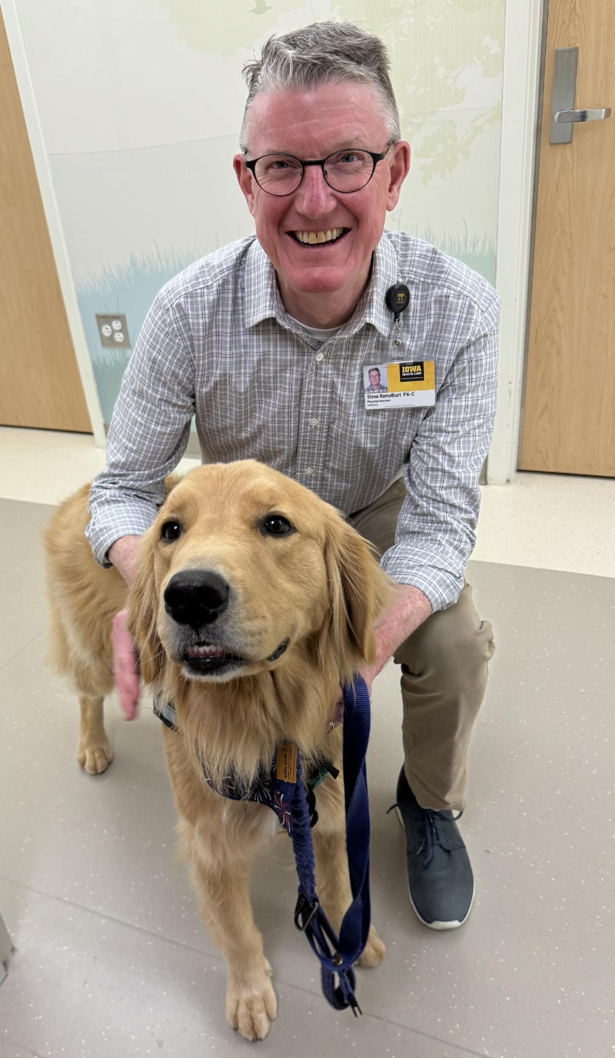 Stephen Rumelhart poses with one of the University of Iowa Health Care facility dogs