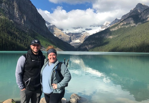 Jordan Williams and his wife, Megan, in front of a mountainside lake view