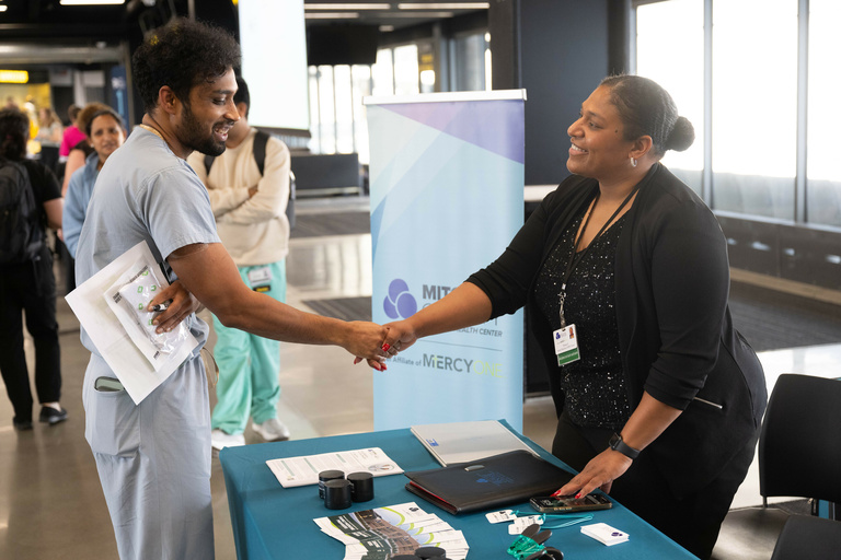 A trainee physician shakes hands with an exhibitor from MercyOne