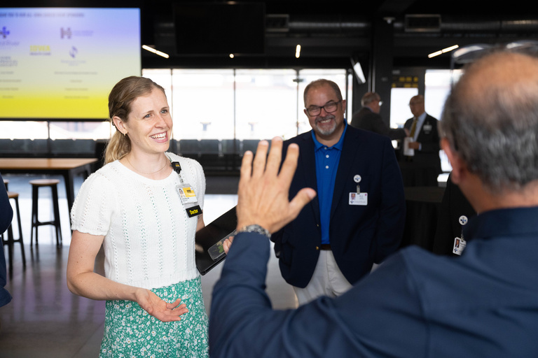 A trainee physician smiles while talking to an exhibitor