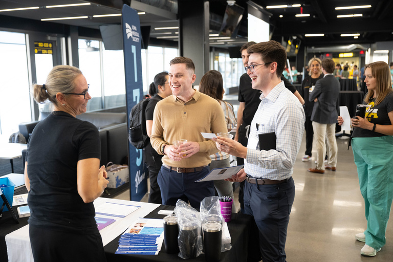 Two individuals speak to an exhibitor from the Iowa Medical Society
